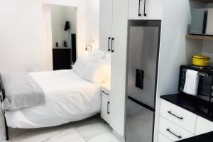 德班North Breeze Retreats的一间白色的小卧室,配有床和微波炉