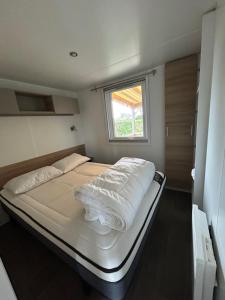 莱马特Mobil'home - Camping **** Les Charmettes的一张位于小房间的大型床,设有窗户