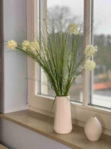 格拉尔-米里茨discovAIR Graal-Müritz -Villa Victoria- Strandnah mit Netflix的窗台上一个白色花瓶,花朵花朵
