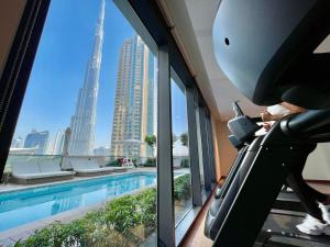 迪拜Stylish New 2BR l Spacious with Burj & Fountain Views l near Dubai Mall l Pool l Gym的站在跑步机上的人,在一座看游泳池的建筑物里