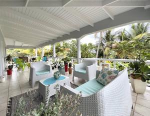 Villa Lu-Ja的一个带白色桌椅和棕榈树的门廊