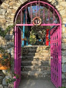 达特恰Eski Datça Pansiyon的石头建筑中设有粉红色的门,设有楼梯