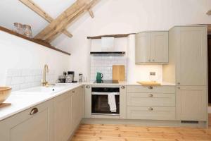 克雷迪顿Spacious country retreat in the heart of Devon.的厨房配有白色橱柜、水槽和烤箱。