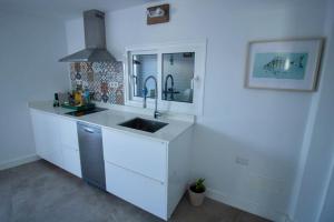 埃尔戈尔福Apartamento Narcisa的白色的厨房配有水槽和镜子