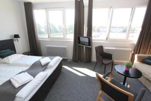 VojensBanegaardshotellet的酒店客房配有床、沙发和电视。