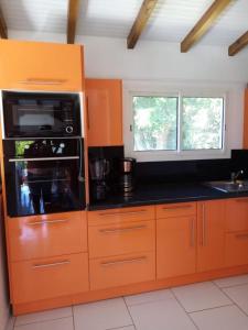 黑角Villa des fleurs的一个带橙色橱柜和微波炉的厨房