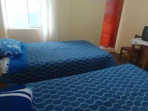 普诺killa andina inn的一间卧室配有两张蓝色床单