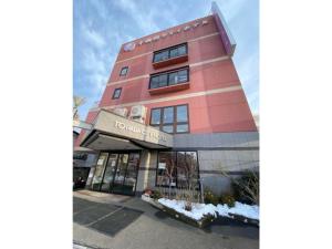 十和田Towada City Hotel - Vacation STAY 85232v的一座高大的粉红色建筑,前面有标志