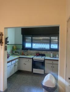 科斯金Lo de Nenè hostal的厨房配有白色橱柜、炉灶和窗户。