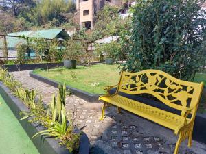 碧瑶Evergreen Suites Cozy Baguio Loft Retreat的坐在花园中的黄色长椅