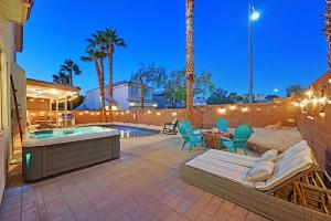 拉斯维加斯Lux Home w Pool, Hot Tub, 4BR, Sleeps 10的庭院设有热水浴池、桌子和椅子。