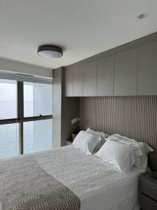 萨尔瓦多Apartamento em Ondina com acesso à praia (Beach Class Salvador)的一间卧室设有一张大床和大窗户