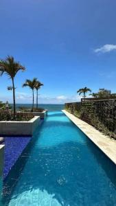 萨尔瓦多Apartamento em Ondina com acesso à praia (Beach Class Salvador)的一座拥有蓝色海水和棕榈树的游泳池