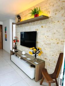 CamassariCondomínio Porto Smeralda的一间客厅,在砖墙上配有电视