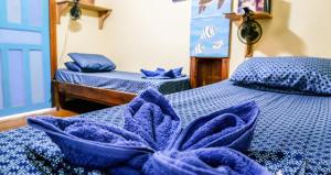 桑迪湾Roatan Backpackers' Hostel的客房设有两张带蓝色床单和枕头的床。