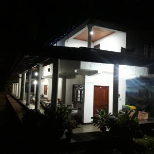 马特莱Geeth Lanka River Resort的一间白色的房子,晚上有棕色的门