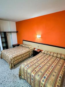 莱昂Hotel Montreal的橙色墙壁的酒店客房内的两张床