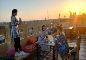 斋沙默尔Hotel Royal Lakhina Jaisalmer的一群女孩坐在阳台上的桌子上