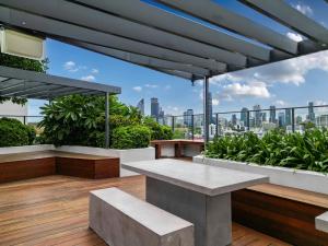 布里斯班Brisbane Luxury Gabba Apartment的一个带长椅的屋顶露台,享有城市美景
