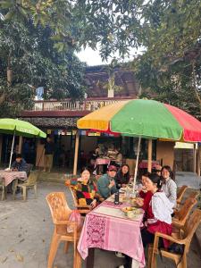 索拉哈Horizon Homes - Sauraha Chitwan的一群人坐在桌子上,在伞下