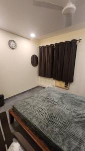 孟买Home sweet home 3BHK的卧室配有一张床,墙上挂着一个钟
