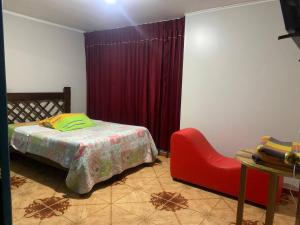 万卡约Hospedaje TOSCANO SUITES的一间卧室配有一张床和一张红色椅子