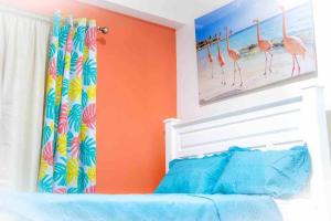 金斯敦Royal Bliss Apartment Suites的一间卧室,墙上装饰有橙色的墙壁,上面装饰有火烈鸟