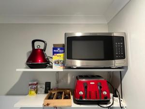 Tura BeachCountry charm coastal living的微波炉烤箱,放在带红色烤面包机的架子上