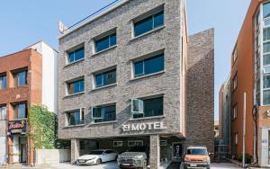 西归浦市Jin Motel的一座砖砌建筑,前面有汽车停放