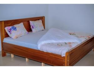 RubavuPlanete Hotel的一张带白色床单和枕头的木床