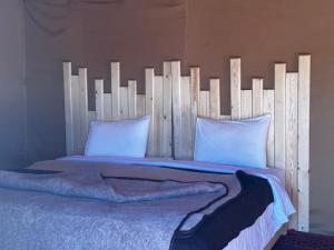 梅尔祖卡Sahara wellness camp的一张带白色枕头的木制床头板的床