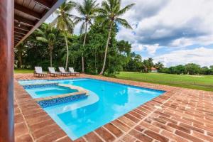 CajuilesBeautiful and Comfortable Four Bedroom Villa的后院的游泳池,设有椅子和棕榈树