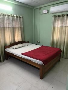古瓦哈提Suryalaxmi guest house的一间卧室配有一张床铺,床上铺有红色毯子