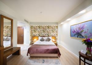布加勒斯特Phoenicia Comfort Hotel的卧室配有一张床,墙上挂有绘画作品