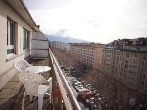 日内瓦Primadom Aparthotel的大楼内的阳台配有两把椅子和一张桌子