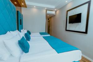 贝尔格莱德Nobel Gallery Hotel的一间卧室配有两张带蓝色枕头的床和电视