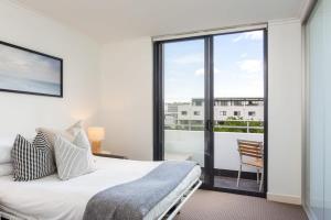 悉尼MadeComfy Executive & Stylish Inner-City Apartment的一间卧室设有一张床和一个阳台