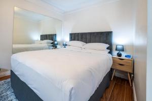 悉尼Sublime Locale with Skyline Views from Courtyard的卧室配有一张白色的大床和床头柜。