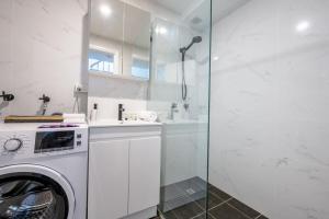 悉尼Sublime Locale with Skyline Views from Courtyard的白色的浴室设有洗衣机和玻璃淋浴间。