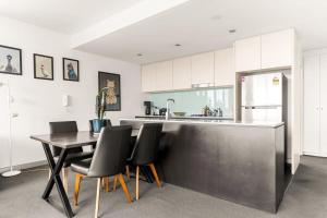 悉尼Spacious 2-Bed with Two Balconies with City Views的厨房配有桌椅和冰箱。