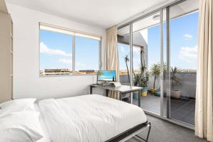 悉尼Spacious 2-Bed with Two Balconies with City Views的一间卧室配有一张床和一张带电脑的书桌
