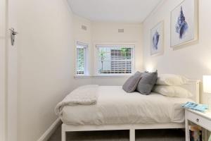 悉尼Art Deco Apartment Meters Away From The Beach的一间白色卧室,配有床和2个窗户