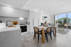 墨尔本Bespoke 2-Bed Beachfront Apartment的厨房以及带桌椅的用餐室。