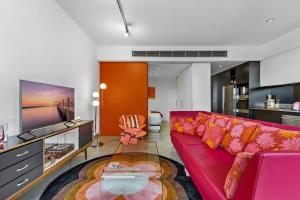 墨尔本Vibrant 2-Bed Apartment Near St Kilda Beach的客厅配有红色的沙发和玻璃桌