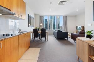 墨尔本Unbeatable 2-Bed Apartment In City Centre的厨房以及带沙发和桌子的客厅。