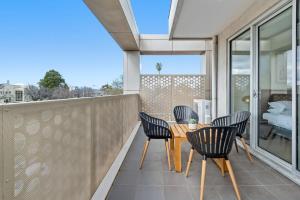 墨尔本Modern 2-bed St Kilda Apartment Near Shops的阳台的天井配有木桌和椅子