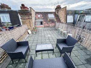 伦敦Lovely 3 bedroom maisonette with private roof terrace in Hammersmith的一座带两把椅子和一张桌子的庭院和一座砖砌建筑