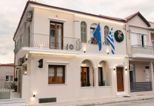 莱瓦贾Aegli Suites的前面有两面旗帜的白色房子