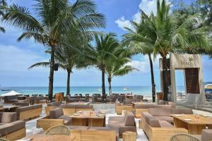 邦涛海滩Arinara Beach Resort Phuket - SHA Extra Plus的海滩上拥有桌子和棕榈树的餐厅