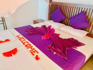 阿鲁特伽马Villa Riverside的一张带紫色床单和紫色餐巾的床